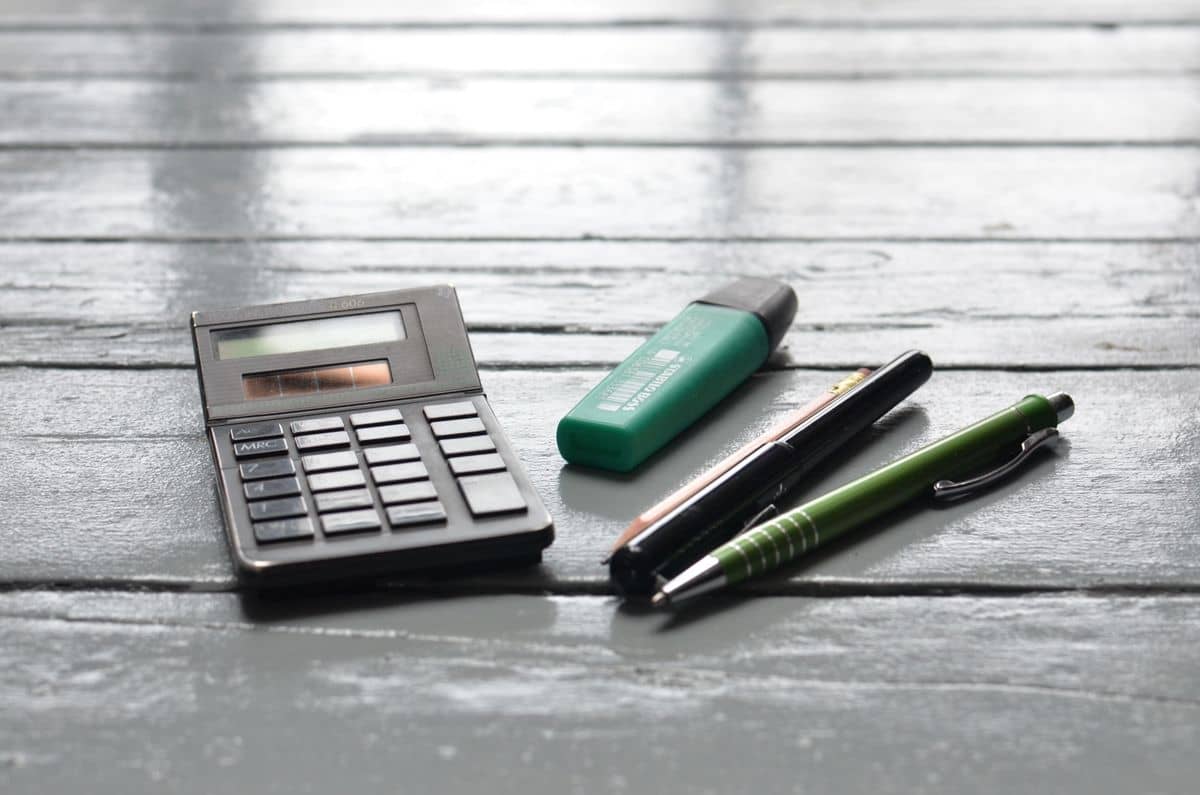 Bookkeeper writing on paper while using a calculator