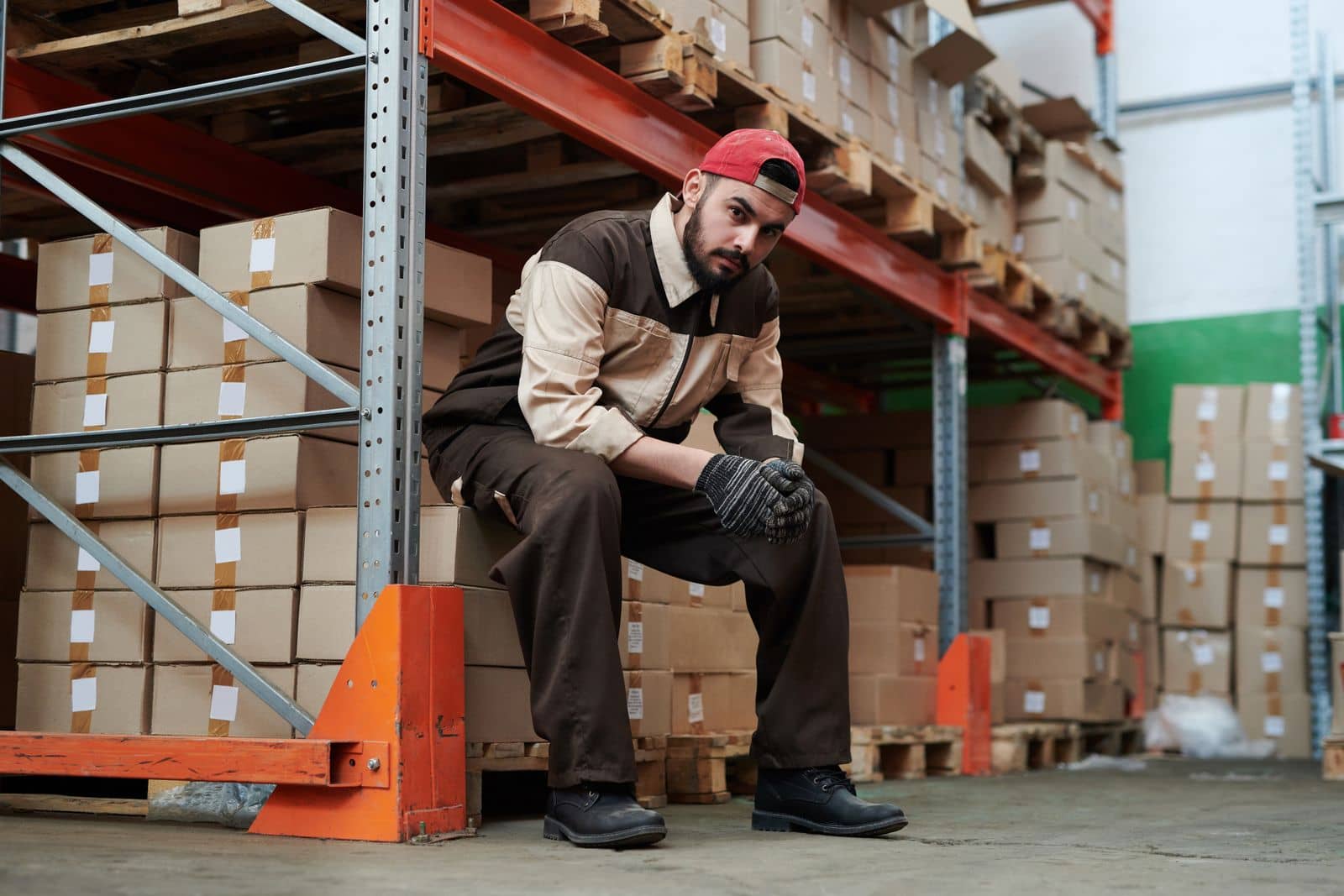 Warehouse worker seated among stacked boxes